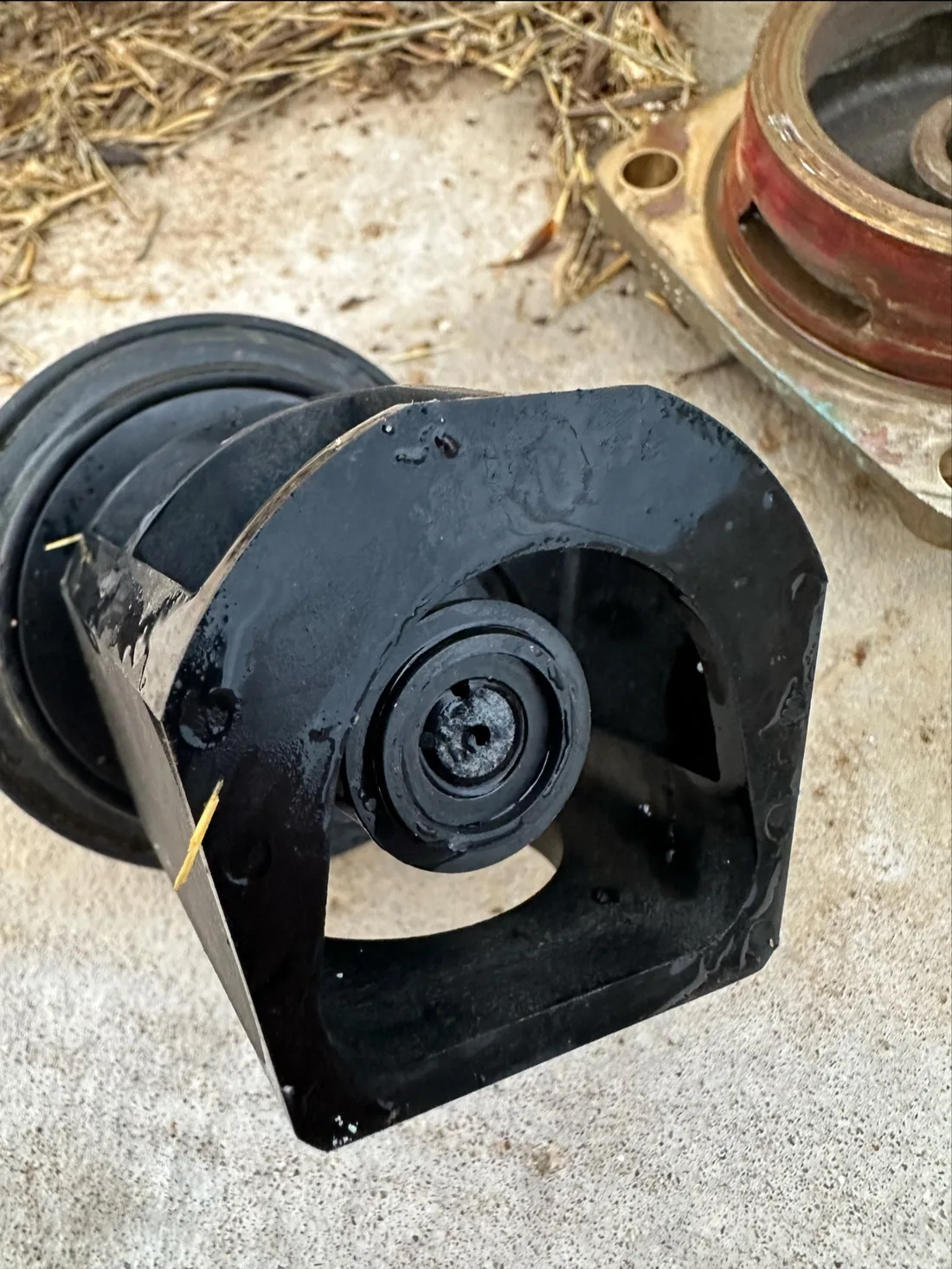 A black cast valve body on concrete, close and dark, the kind of hardware a backflow repair actually involves