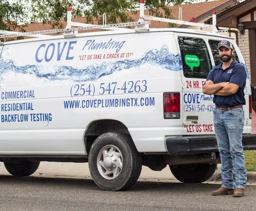 A Cove Plumbing technician standing beside the branded service van